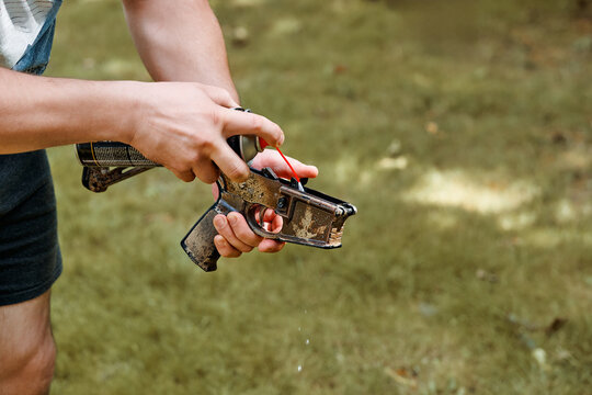 Handgun AR rifle lower Cleaning And Maintenance With Spray Oil On Rusty Pistol Held Outdoors By Hands