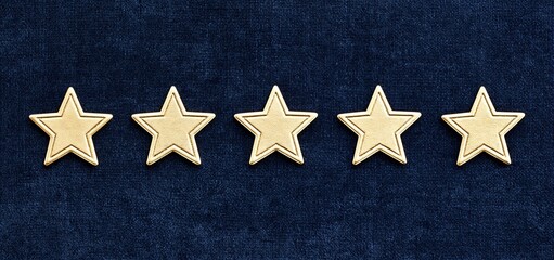 Fototapeta premium On a dark velvet surface, a row of sophisticated gold star decorations ideal for upscale holiday or event designs.