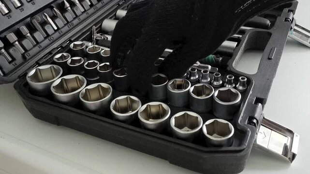 Mechanic taking socket attachments for ratchet wrench from tool case with sockets, auto repair, maintenance, construction and mechanical work concept.