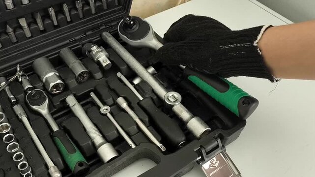 Mechanic taking ratchet wrench from tool case with sockets, auto repair, maintenance, construction and mechanical work concept.