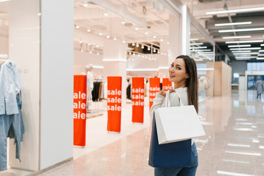 Smiling Woman Posing with Shopping Bags near Retail Display