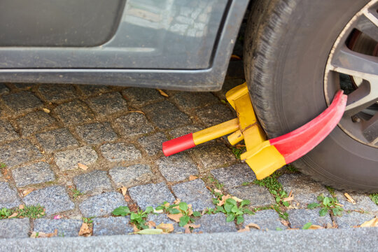 Parkkralle (Radkralle) an Autoreifen von Falschparker Auto auf Kopfsteinpflaster