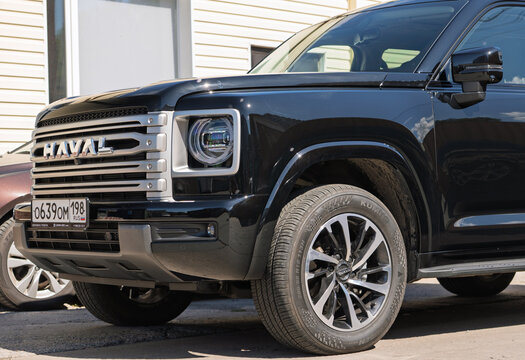 Black modern Haval H9 SUV car with protective polyurethane paint protection film PPF wrapped on body bodywork parked on an urban street near building facade, exterior view of premium chinese SUV car. 