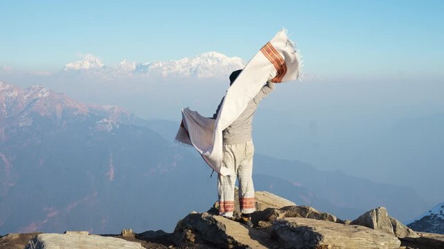 Hiker with shawl at Tungnath temple in Chopta Uttarakhand overlooking Himalayan mountains