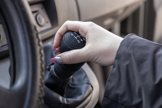 A driver hand grips the gear stick inside a modern vehicle while shifting gears for manual driving to highlight the mechanical operation of automotive transport travel today