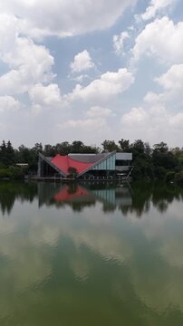 Vertical aerial panning view over Lago Mayor with modern pavilion reflection, Bosque de Chapultepec, vertical video, Mexico City, shot in D-Log M