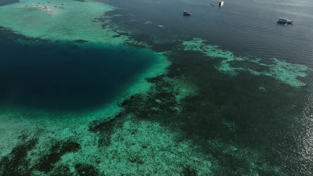 Aerial view of Taka Makasar coral reef with turquoise waters and vibrant marine life in Komodo, East Nusa Tenggara, Indonesia.