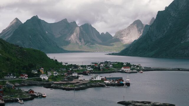 Sunlight reaches a quiet waterfront settlement beneath alpine peaks
