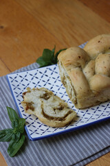Fototapeta premium Braided bread with green basil pesto sauce on a decorated ceramic tray on wooden table with copy space