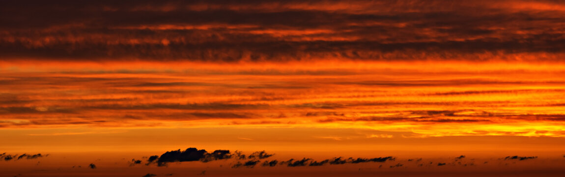 A colorful sunset in the sky with layered striped clouds