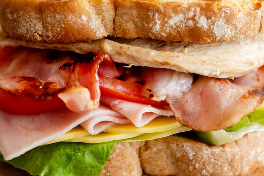 Grilled club sandwich with bacon and ham on wooden table. Copy space