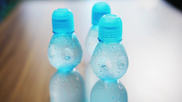 Three chilled blue capped bottles in a row, shallow focus on nearest cap