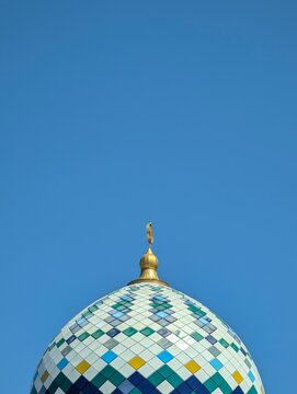 Colorful Mosaic Mosque Dome With Golden Finial Against Blue Sky