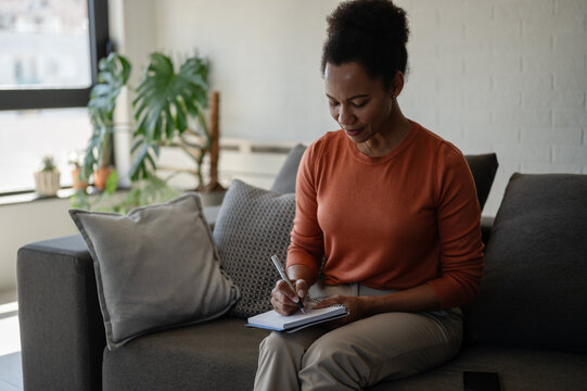 writing, taking notes, note taking, planning, planner, notebook, writing notes, woman writing, woman, adult woman, focused, concentration, concentrating, organizing, organization, personal organizatio