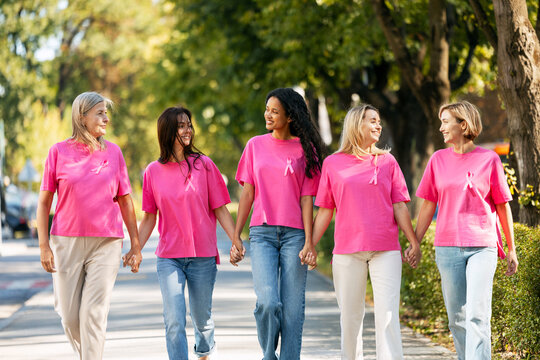Women holding hands walking for breast cancer awareness