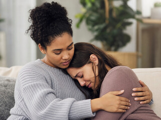 Obraz premium Young woman comforting her crying friend with a warm hug indoors