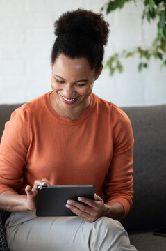 Happy woman smiles while using a digital tablet at home, reacting positively to good news, a message or online content