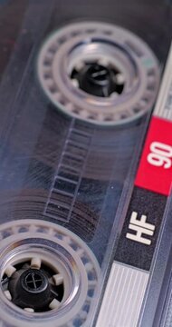 Spinning Cassette Reel Close-Up. Macro view of magnetic tape reel rotating inside a transparent audio cassette with shallow focus.