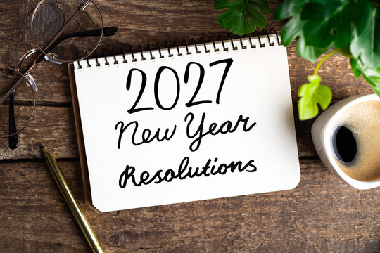 New year resolutions 2027 on desk. 2027 goals list with notebook, coffee cup, plant on wooden table. Resolutions, plan, goals, action, checklist, idea concept. New Year 2027 resolutions. Copy space