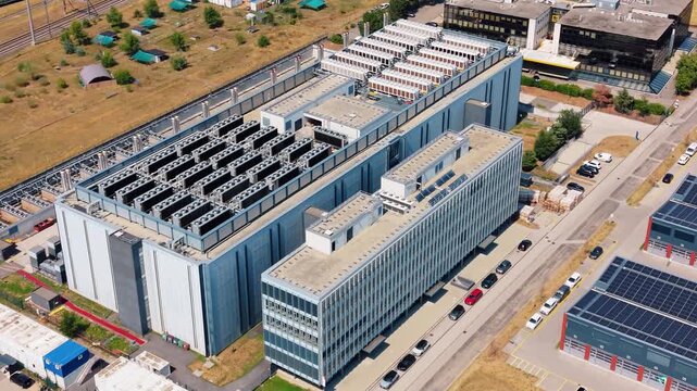 Aerial view of STACK Infrastructure GEN02A Data Center with rooftop cooling units and adjacent parking lot in Gland, Vaud, Switzerland.