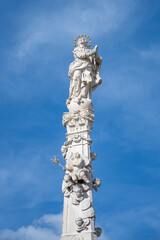 Fototapeta premium The Marian Column is located in Masaryk Square in Trebon. It features a statue of the Virgin Mary and angels. The setting has clear blue skies and is a notable landmark.