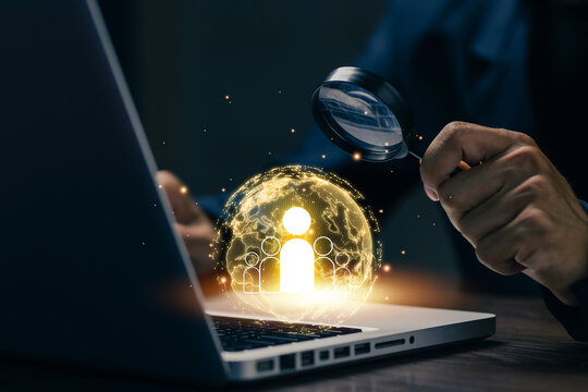 Business professional uses magnifying glass to search global talent on laptop, illustrating recruitment, hiring, human resources, candidate selection, workforce, and digital networking.