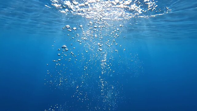 Underwater air bubbles rise toward the surface, expanding into shimmering clusters during a peaceful deep water movement sequence
