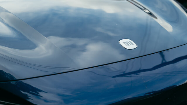 Smolensk, Russia 08.08.2026 Xiaomi SU7 A car hood captures reflections of clouds in the sky on a bright day. The hood has a circular logo visible in the center, adding detail to the scene