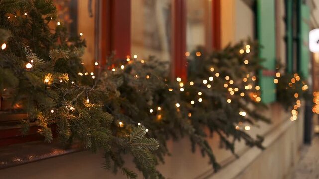 Atmospheric video of warm golden Christmas string lights illuminating outside a window pane during winter holidays at night.