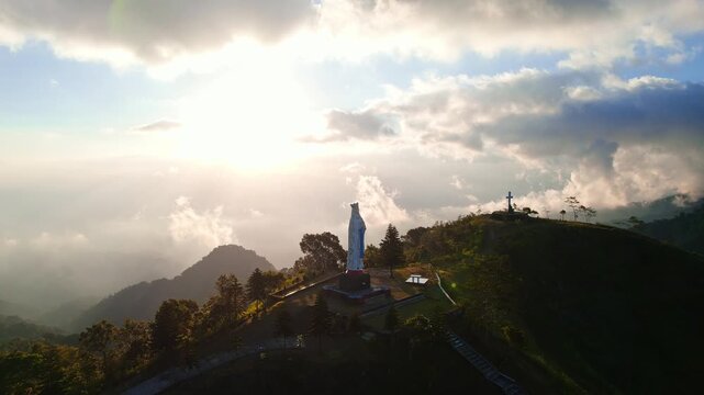 Aerial view of the Patung Bunda Maria Ratu Semesta Alam Wolo Ata Ga'e statue atop a lush hill in Bajawa, Nusa Tenggara Timur, Indonesia.