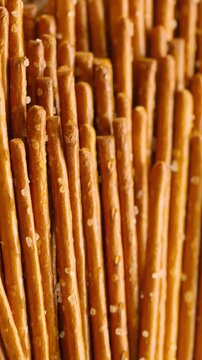 Salted Pretzel Sticks Texture. Macro view of golden brown pretzel sticks covered with coarse salt crystals.