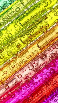 Colorful Liquid Bubbles in Transparent Tubes. Macro view of numerous air bubbles moving through yellow, orange and pink liquid inside parallel transparent tubes.