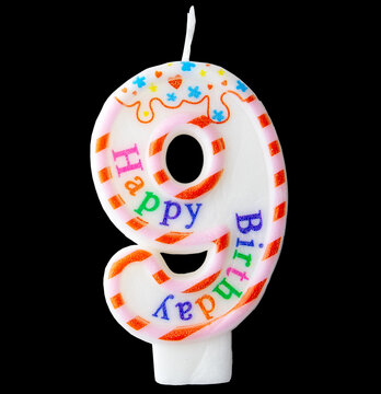 Number nine shaped birthday candle with colorful sprinkles and Happy Birthday text isolated on a black background