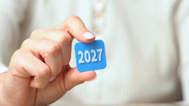 2027: A woman holds the icon with her fingers. Business plans and economic forecasts. Strategic vision, market expectations and financial planning. Corporate strategy content