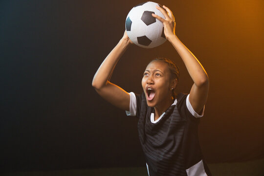 Adult African woman holding BW ball overhead shouting in BW-jersey braids ring warm-rim, copy space