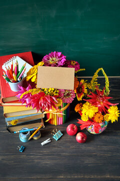 Empty greeting card with flowers, books, school stationery, apples on table. Education, back to school, beginning of the school year, Teacher's day, Knowledge Day, 1 September concept. copy space