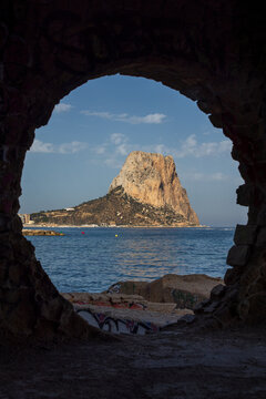 View of the Penyal d'Ifac rock formation framed by a stone archway overlooking the Mediterranean Sea in Calp, Valencian Community, Spain.