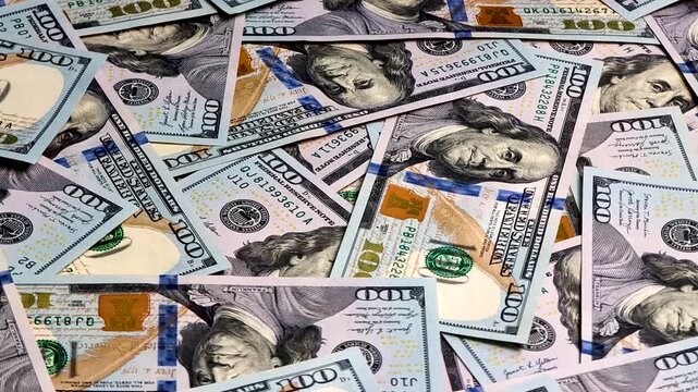 Video of floating 100 dollar banknotes rotating in a circular motion from an angled perspective. Dynamic money background in 4K resolution Finance concept