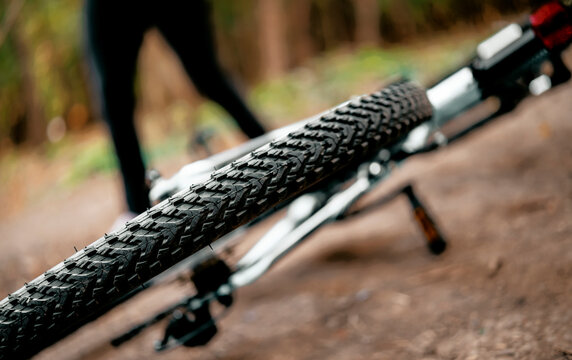 Close up of bicycle tire tread on dirt road in woods. Technical details of mountain bike for intense cardio workout in nature.