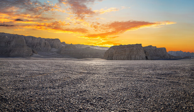 Vast gravel desert with yardang landforms under a dramatic golden sunset sky in Dahaidao, Gobi Desert, Xinjiang, China