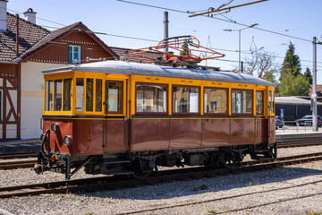 Fototapeta premium A classic vintage electric railcar with a yellow and brown wooden body parked outside the train depot at Attersee on a sunny day.