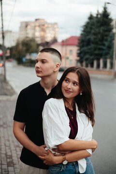 Young couple embracing on city street looking forward
