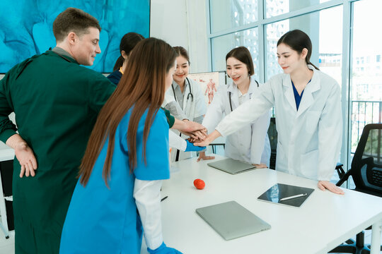 Medical team of doctors and nurses stacking hands in unity during clinic meeting