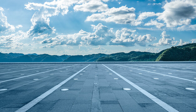 Empty paved plaza floor and green mountains under blue sky as background