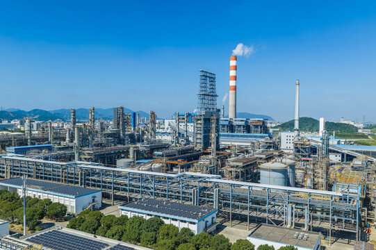 Aerial view of a modern petrochemical refinery with pipelines and smokestacks under a blue sky in China