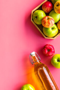 Apple cider in bottle near tray with fruits on pink background top view space for text