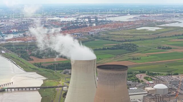 Aerial view of the doel nuclear power station on the banks of the scheldt river in belgium with cooling towers emitting steam