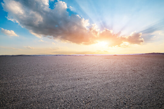 Vast empty gravel desert under a dramatic sky with bright sunbeams in Xinjiang, China