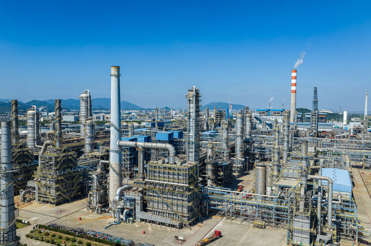 Aerial view of a modern petrochemical refinery with pipelines and smokestacks under a blue sky in China