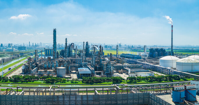 Aerial view of a modern petrochemical refinery with pipelines and smokestacks under a blue sky in China
